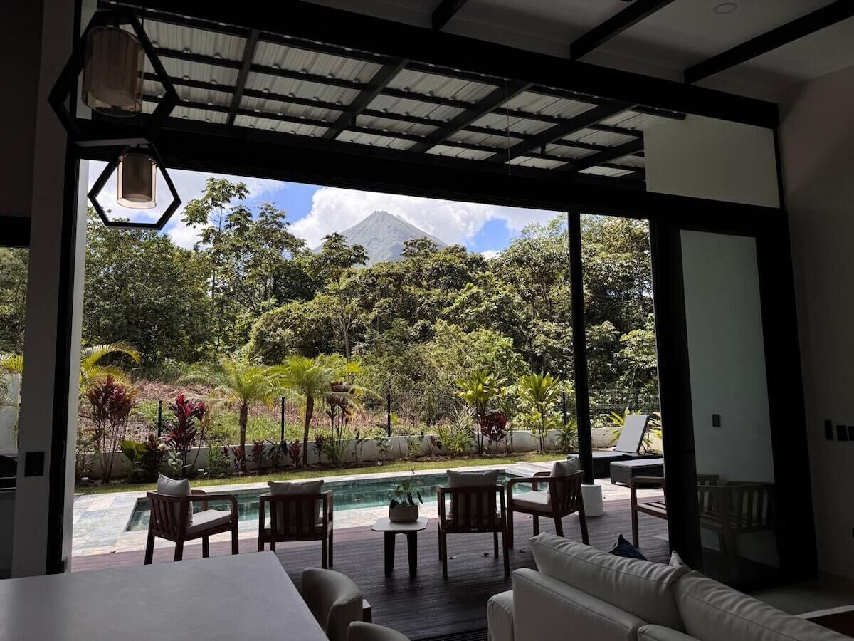 A modern interior with a view of a pool and lush greenery outside.
