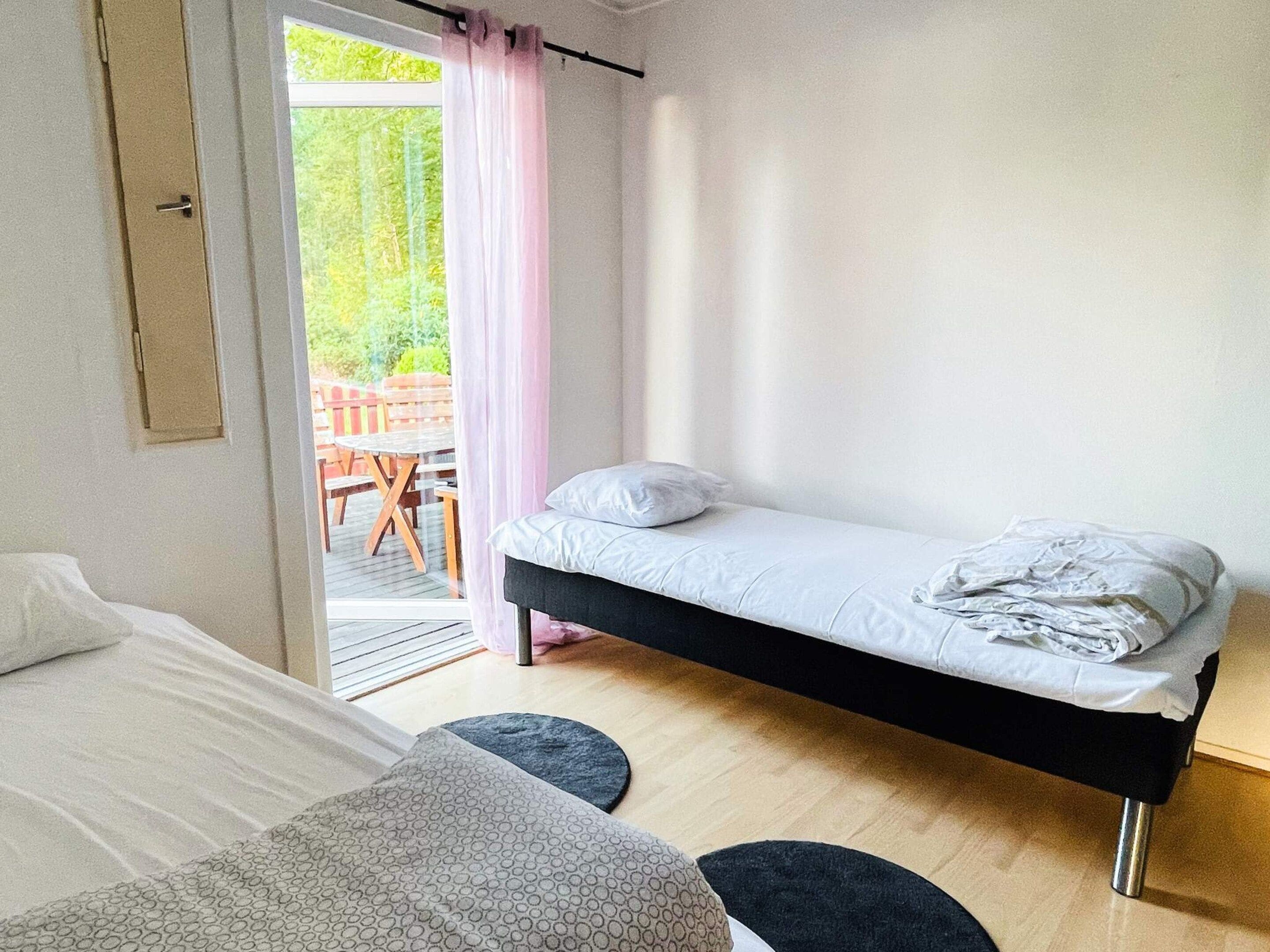 Quarto com uma cama de solteiro, uma mesinha e vista para um pátio externo.
