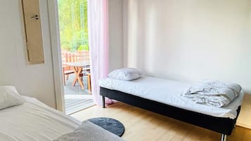 Quarto com uma cama de solteiro, uma mesinha e vista para um pátio externo.