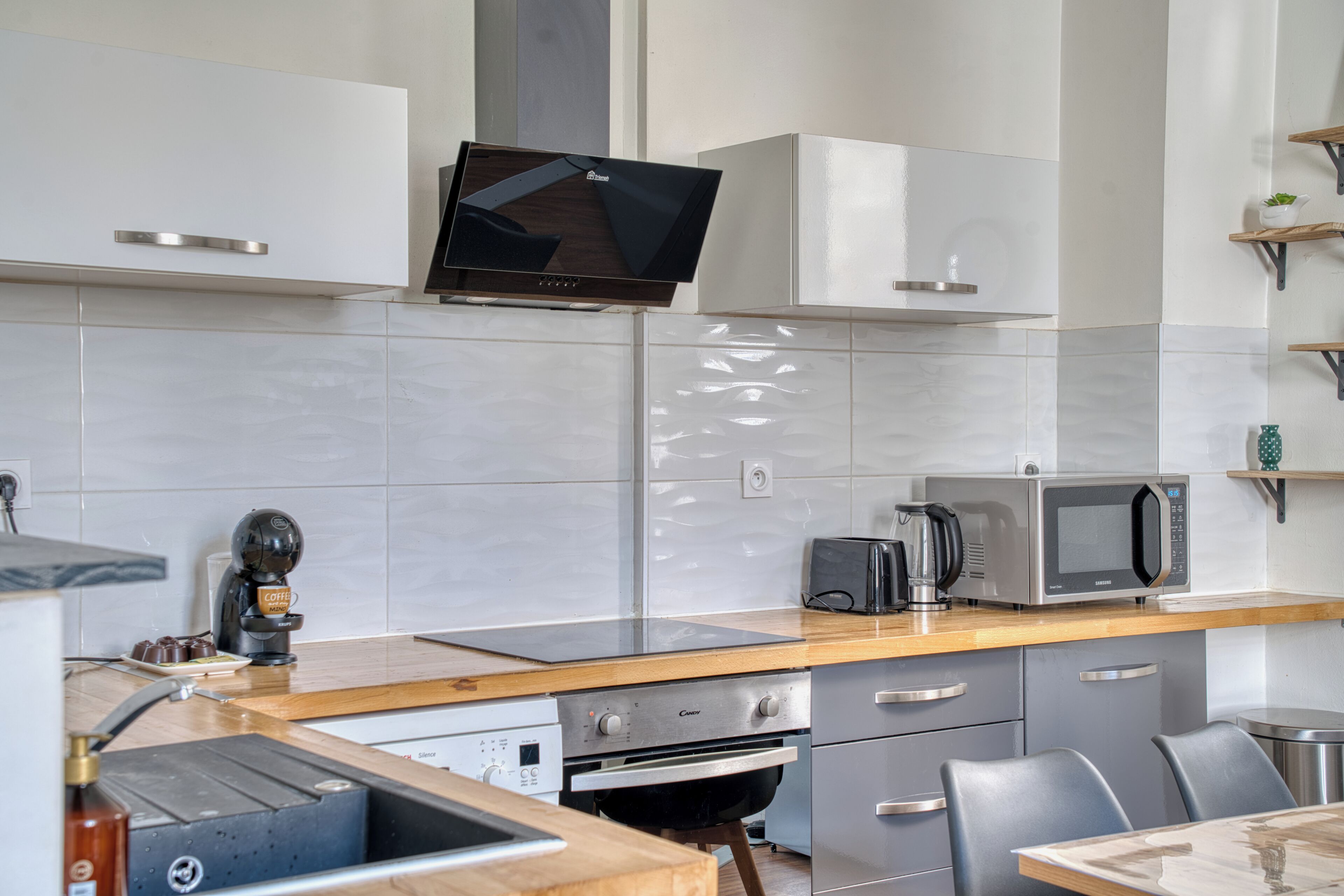 A modern kitchen with a built-in microwave, toaster, and coffee machine.