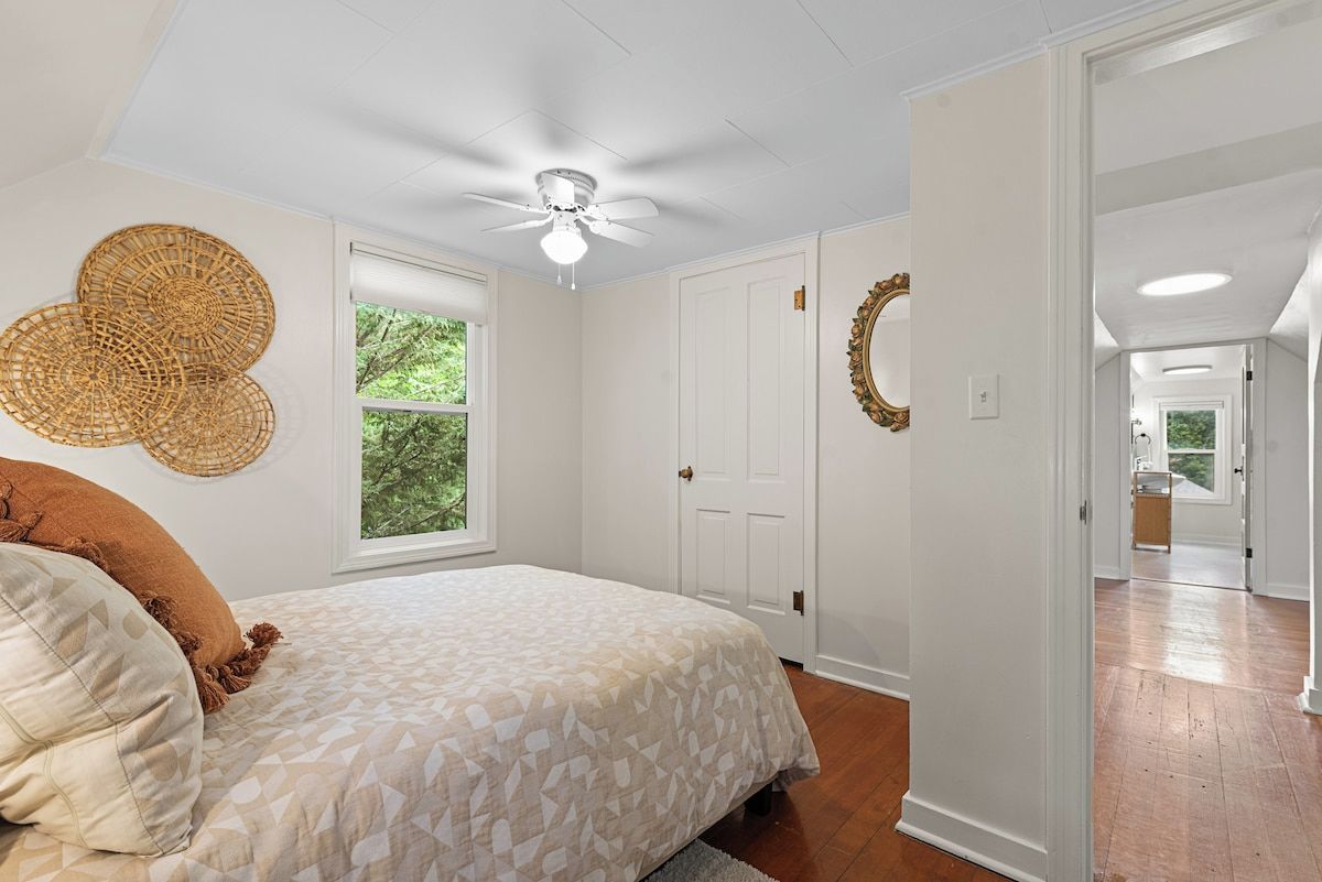 Quarto com cama, ventoinha no teto, janela e porta.