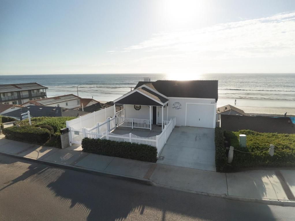 A coastal property with a white building featuring a porch, a garage, and a view of the ocean.