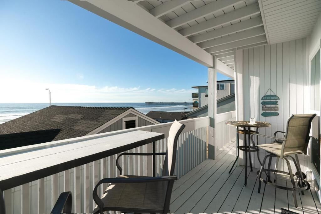 A wooden deck with a view of the ocean, a table, and two chairs.