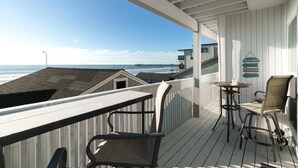 A wooden deck with a view of the ocean, a table, and two chairs. - Fabulous 2 bed Home in Oceanside, beachfront access with stunning sea views (Oceanside)