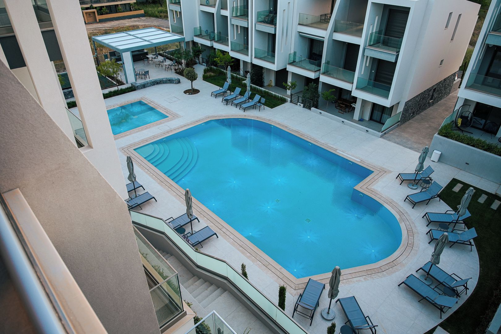 A rooftop pool area with multiple levels of balconies, lounge chairs, and a clear blue pool.