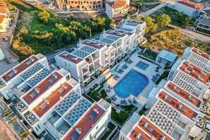 Un edificio residencial moderno con varios balcones, una piscina y un jardín ajardinado.