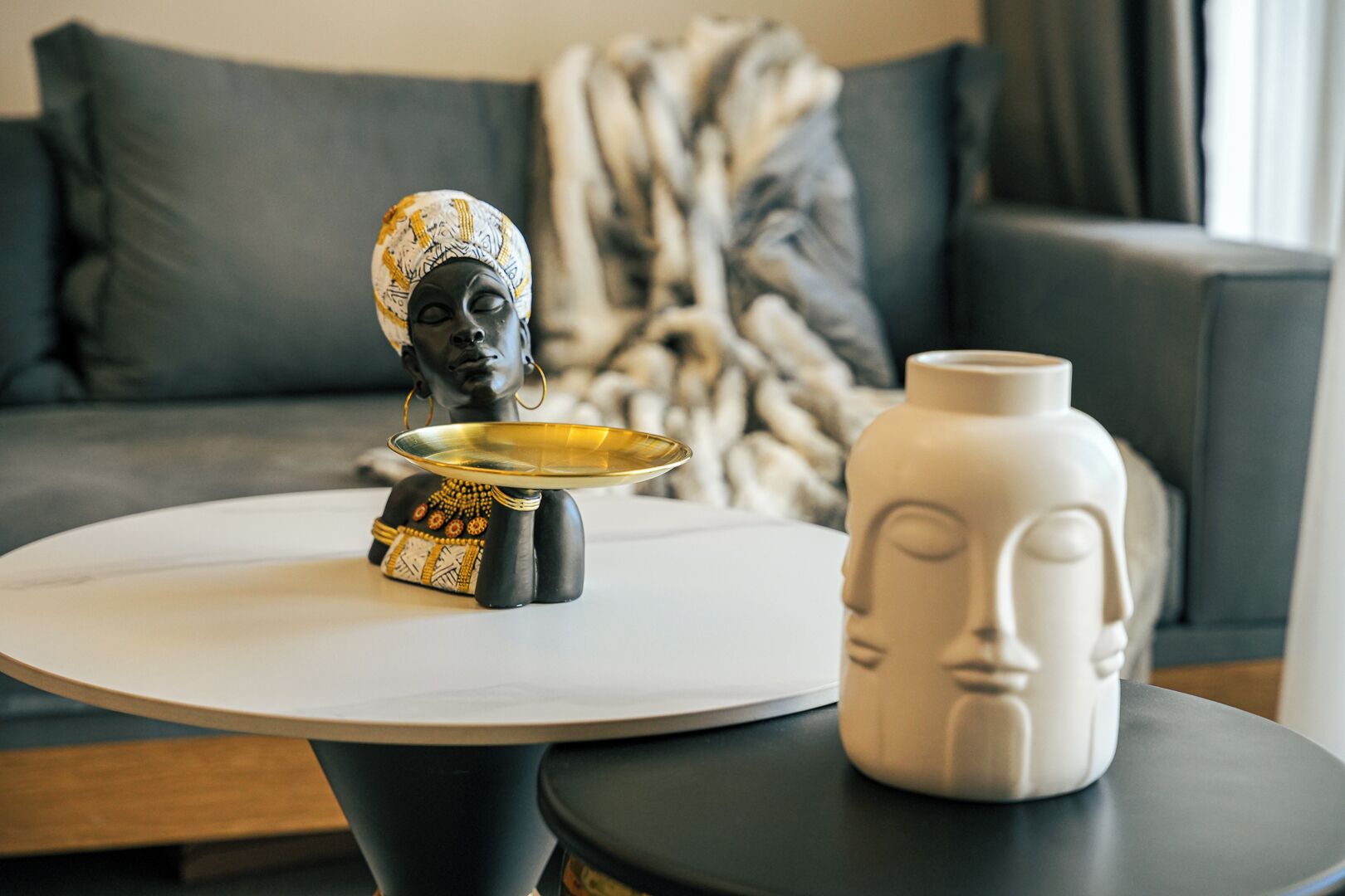 Una mesa redonda con una escultura decorativa y un florero.