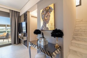 A modern hotel room with a balcony, a flat-screen TV, a console table with decorative items, and a painting on the wall. - ARTION HOT TUB SEA VIEW NIKITI elegant 3 bedroom Villa-hot tub jacuzzi &sea view (Nikiti)