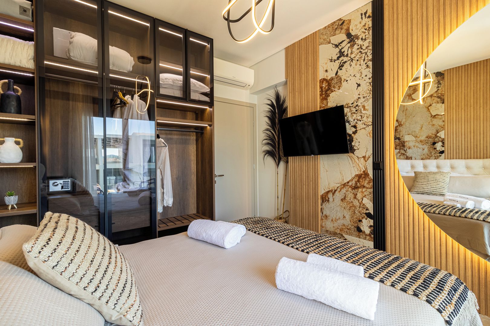 Un dormitorio moderno con vestidor, televisión de pantalla plana y un espejo grande.