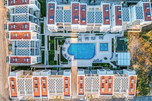 An aerial view of a modern residential complex with multiple apartment buildings, a central swimming pool, and outdoor seating areas. - ARTION HOT TUB SEA VIEW NIKITI elegant 3 bedroom Villa-hot tub jacuzzi &sea view (Nikiti)