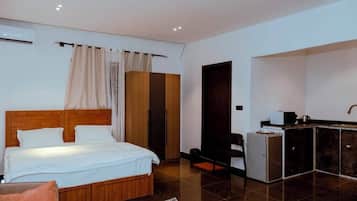 Een slaapkamer met een houten bed, een klein kitchenette en een kledingkast.
