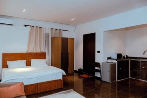 A bedroom with a wooden bed, a small kitchenette, and a wardrobe.