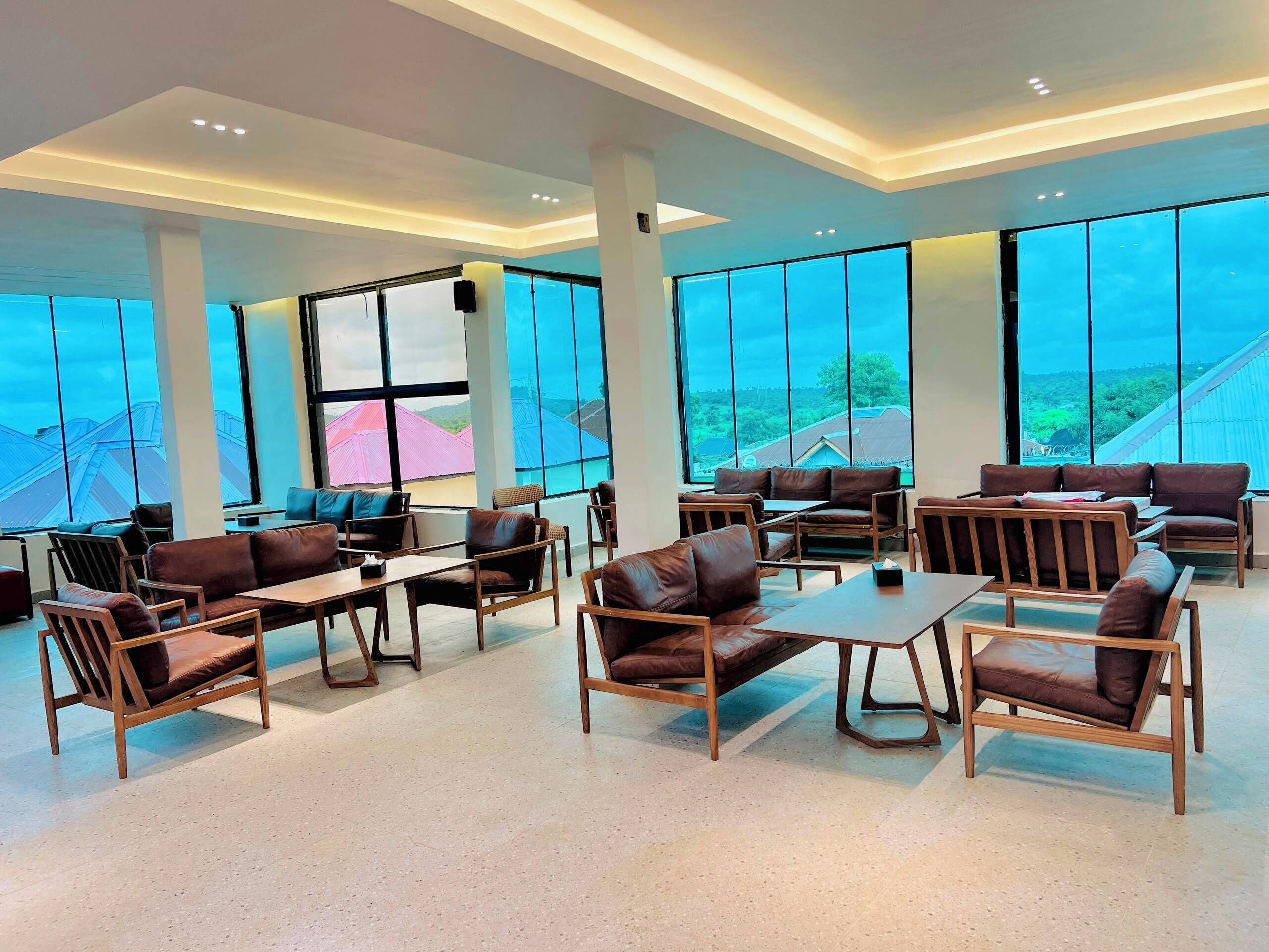 Un espace intérieur spacieux avec de grandes fenêtres, des canapés en cuir et des tables en bois.