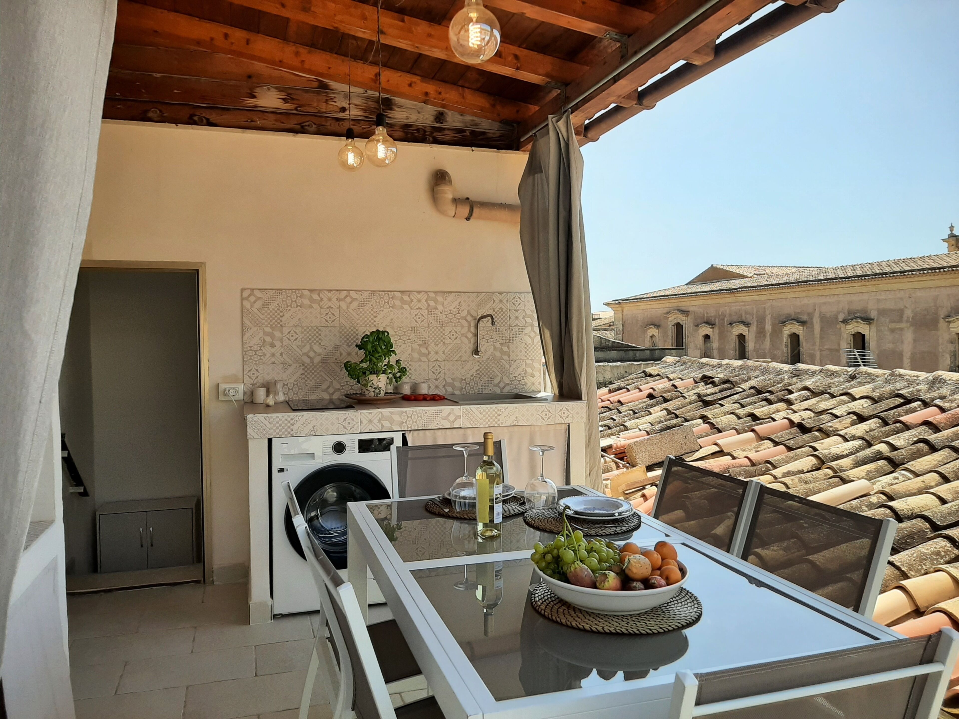 A balcony with a table set for dining, a washing machine, and a potted plant.