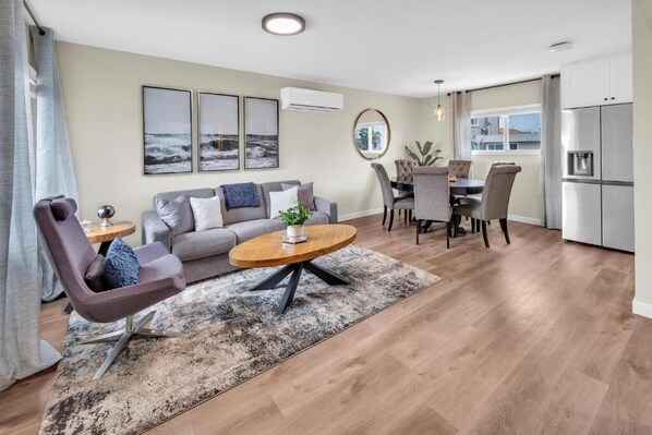 Uma sala de estar moderna com sofá, mesa de centro e área de refeições.