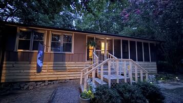 A wooden cabin with a porch and steps leading to a door.