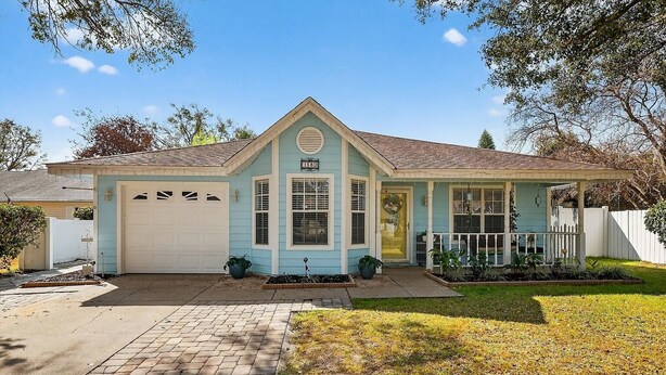 A single-story house with a garage, a front porch, and a well-maintained lawn. - 3-bedroom cottage in adorable Mount Dora with AC comfort (Mount Dora)