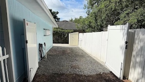A gravel driveway leading to a building with a white fence and a blue exterior. - 3-bedroom cottage in adorable Mount Dora with AC comfort (Mount Dora)