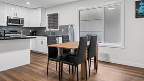 Une cuisine moderne avec des meubles blancs, un four à micro-ondes et une machine à café.