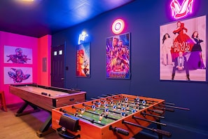 Ein Zimmer mit Kicker, Postern an der Wand und einer Neonreklame.