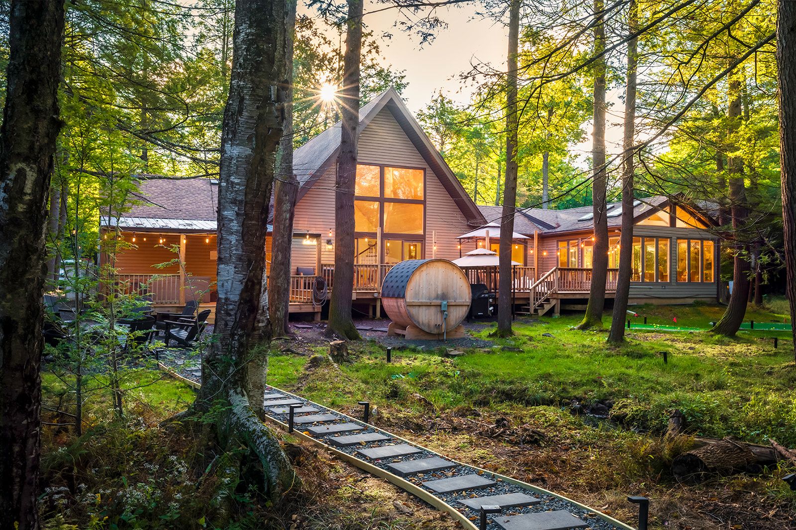 Eine Hütte mit einer Terrasse, einem Fass und einem Holzweg.