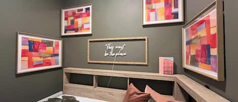 Ein Schlafzimmer mit einem Bett, einem Kopfteil, einem Wandregal und vier gerahmten Kunstwerken.