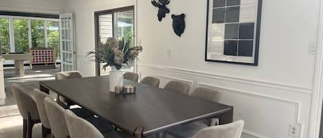 A dining area with a long table and chairs, a vase with flowers, and wall-mounted animal head decorations.