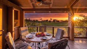 Un comedor con una mesa dispuesta para cuatro personas, con vista a un campo de golf al atardecer.
