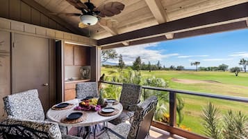 Balcón con mesa dispuesta para comer, con vista a un campo de golf.