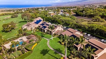 Una zona residencial con casas, un campo de golf y un edificio grande con paneles solares.