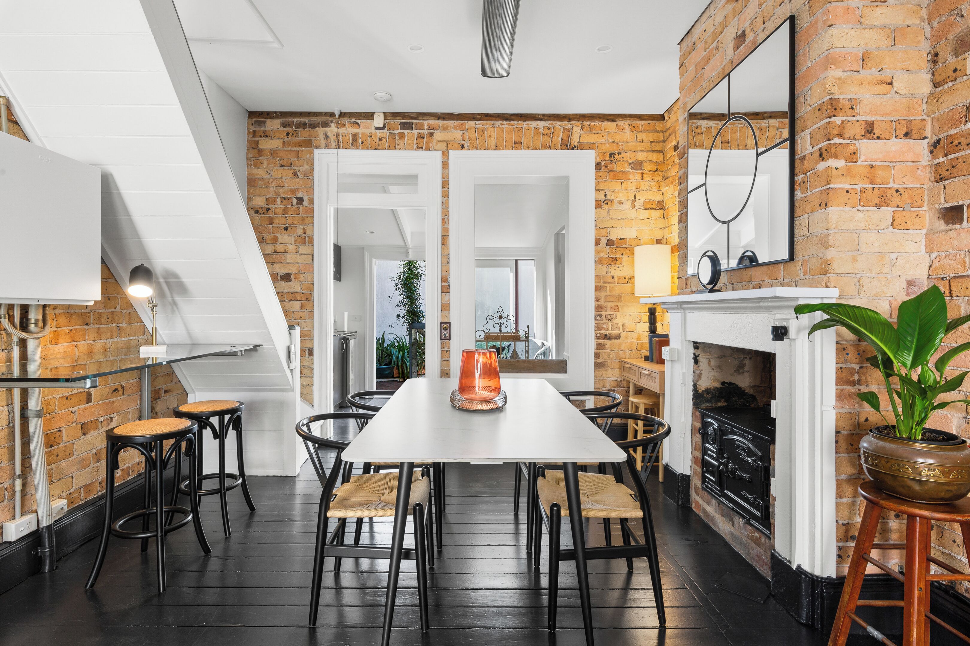 Un coin repas avec un mur en briques, une cheminée et une vue sur une autre pièce.