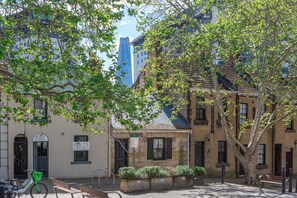 A street scene with a building that has a sign for 'PYRMONT Tailoring & Alterations'. There is a bicycle parked in front of the building.