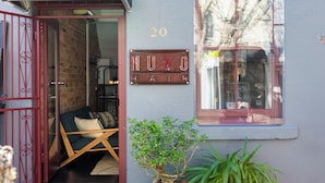 L'ingresso di un edificio con un cancello rosso, una insegna con su scritto 'NUVO AIR' e una piccola pianta in vaso.