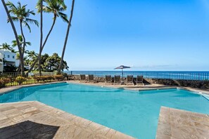 A swimming pool with lounge chairs and a view of the ocean. - Royal Seacliff#401 (Kailua-Kona)