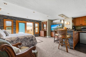 A bedroom with a large bed, a desk, and a view of the outdoors. - Kona Alii#704: 7th Floor Penthouse, Oceanfront! (Kailua-Kona)