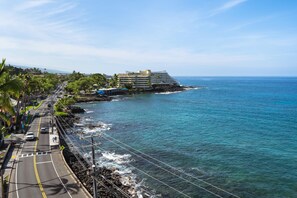A coastal road with a hotel on a cliff overlooking the ocean. - Kona Alii#704: 7th Floor Penthouse, Oceanfront! (Kailua-Kona)