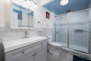 Ein modernes Badezimmer mit einem weißen Waschtisch, einer Glasdusche und einer Toilette.