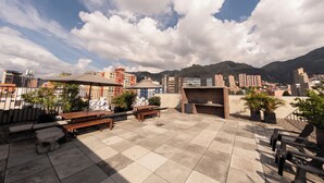 A rooftop patio with seating, a barbecue area, and a view of a cityscape and mountains. - Studio artístico Chapinero Alto Zona G (Bogotá)