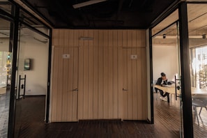 Ein Zimmer mit einer Holzwand, einer Tür und einer Person, die an einem Tisch mit einem Laptop sitzt.