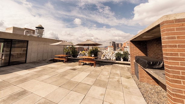 A rooftop patio with outdoor seating, a brick wall, and a view of the city skyline. - Studio artístico Chapinero Alto Zona G (Bogotá)
