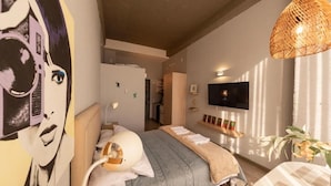 A bedroom with a bed, a television, and a wall-mounted shelf with books. - Studio artístico Chapinero Alto Zona G (Bogotá)