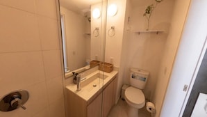 A compact bathroom with a toilet, sink, and a glass shower enclosure. - Studio artístico Chapinero Alto Zona G (Bogotá)
