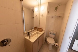 A compact bathroom with a toilet, sink, and a glass shower enclosure. - Studio artístico Chapinero Alto Zona G (Bogotá)