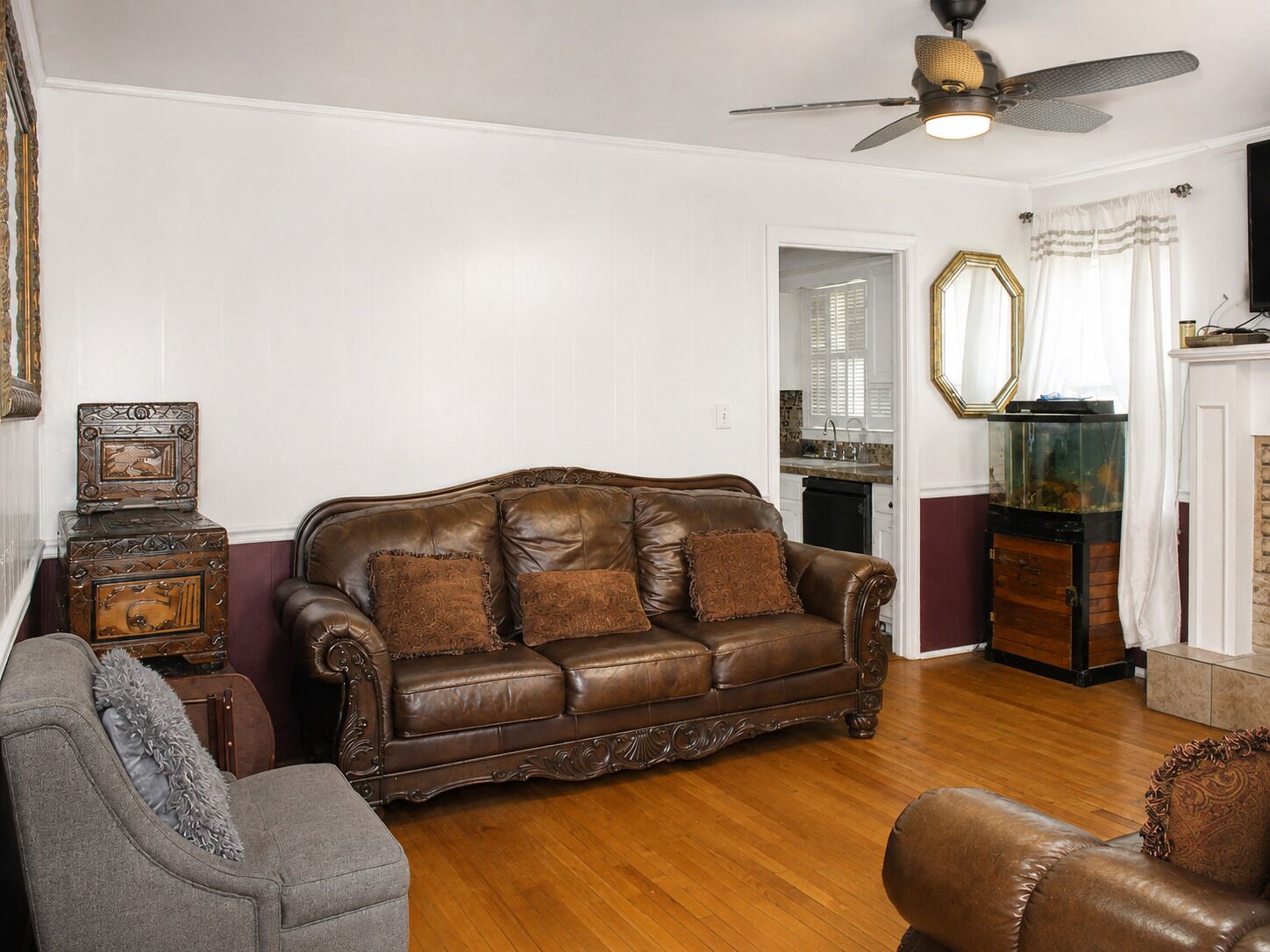 Ein Wohnzimmer mit einem braunen Ledersofa, einem grauen Sessel und einer Holzkommode.