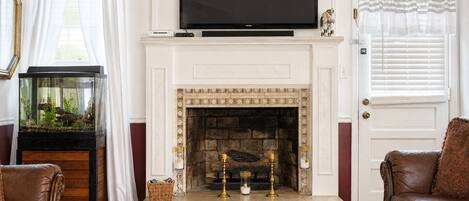 A living room with a fireplace, a television mounted above it, and a fish tank to the left.