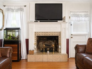 A living room with a fireplace, a television mounted above it, and a fish tank to the left.