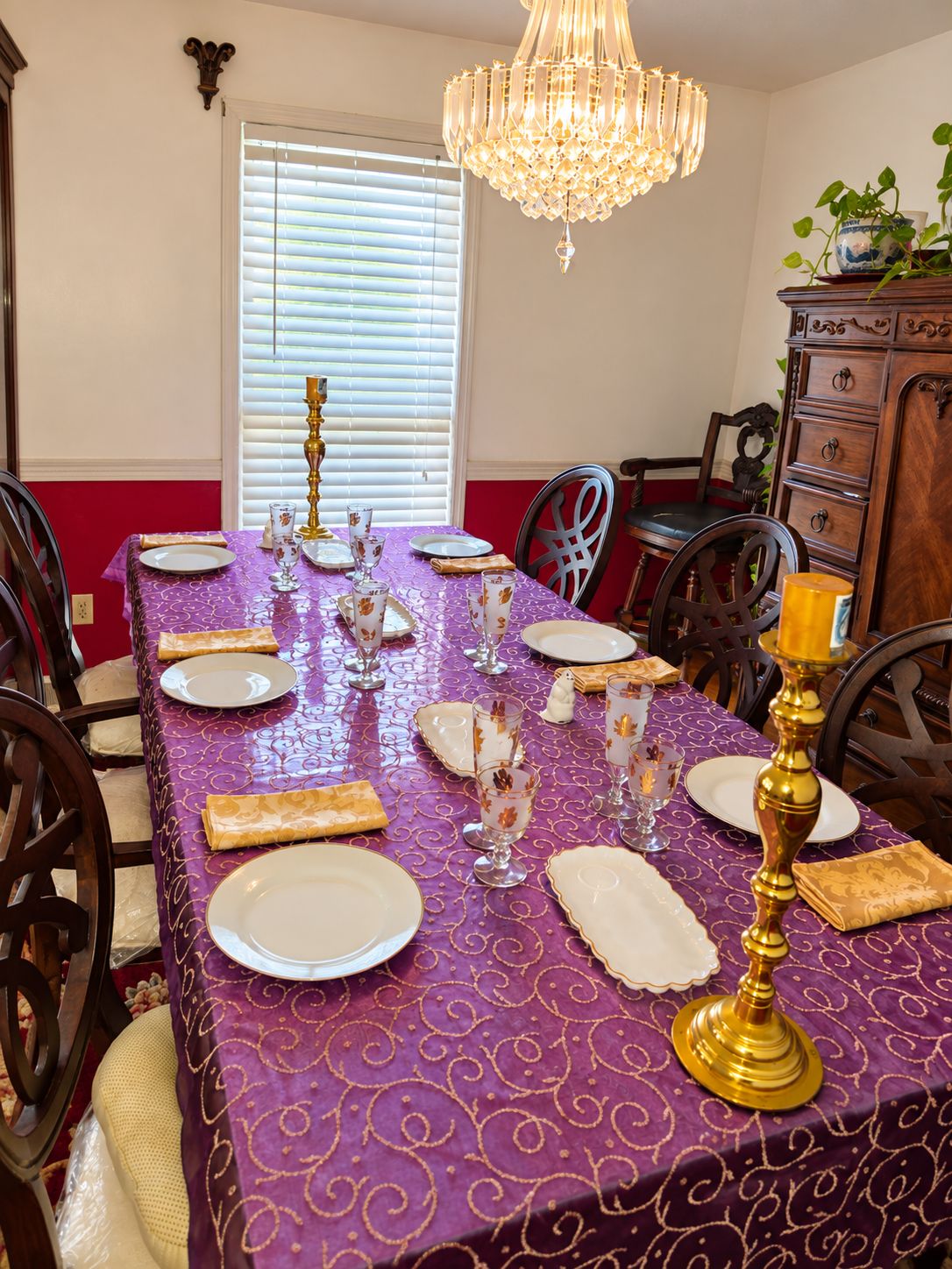 A dining table set with plates, glasses, and a candelabra, surrounded by chairs.