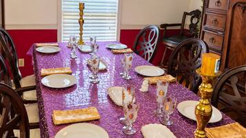 A dining table set with plates, glasses, and a candelabra, surrounded by chairs.