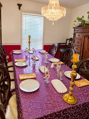 A dining table set with plates, glasses, and a candelabra, surrounded by chairs.