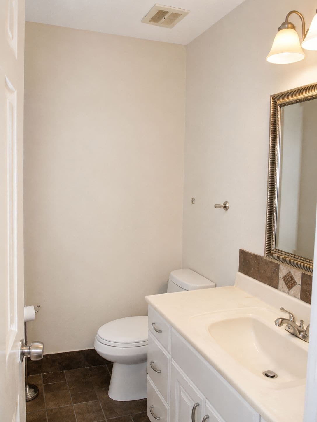 Un baño con inodoro, lavamanos y espejo.